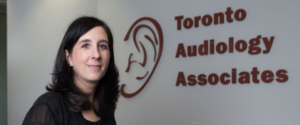Registered Audiologist in Toronto in front of Toronto Audiology Associates clinic sign